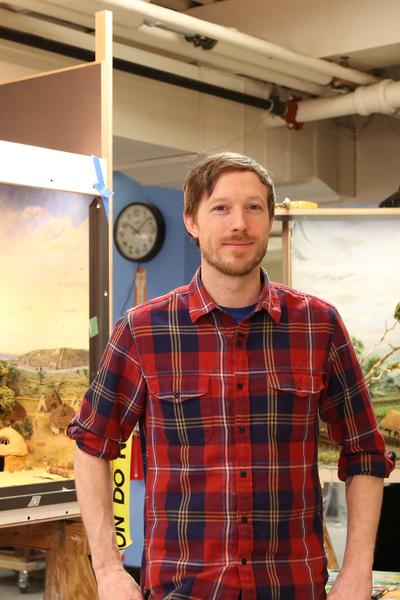 Photo of Aaron Delehanty with two landscape paintings