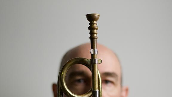 Artistic photo of Dr. Tom Pfotenhauer posed with a trumpet in the foreground