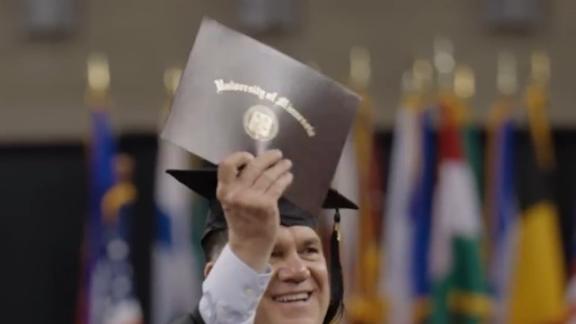 photo of a white man holding UMD master of professional studies diploma