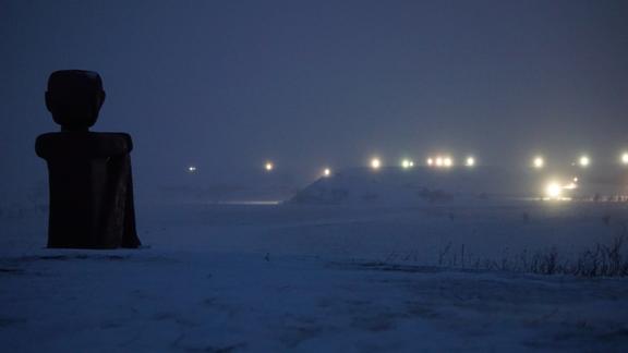 photo of sculpture overlooking industrial lights in the snow