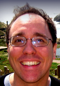 White man in glasses smiling.
