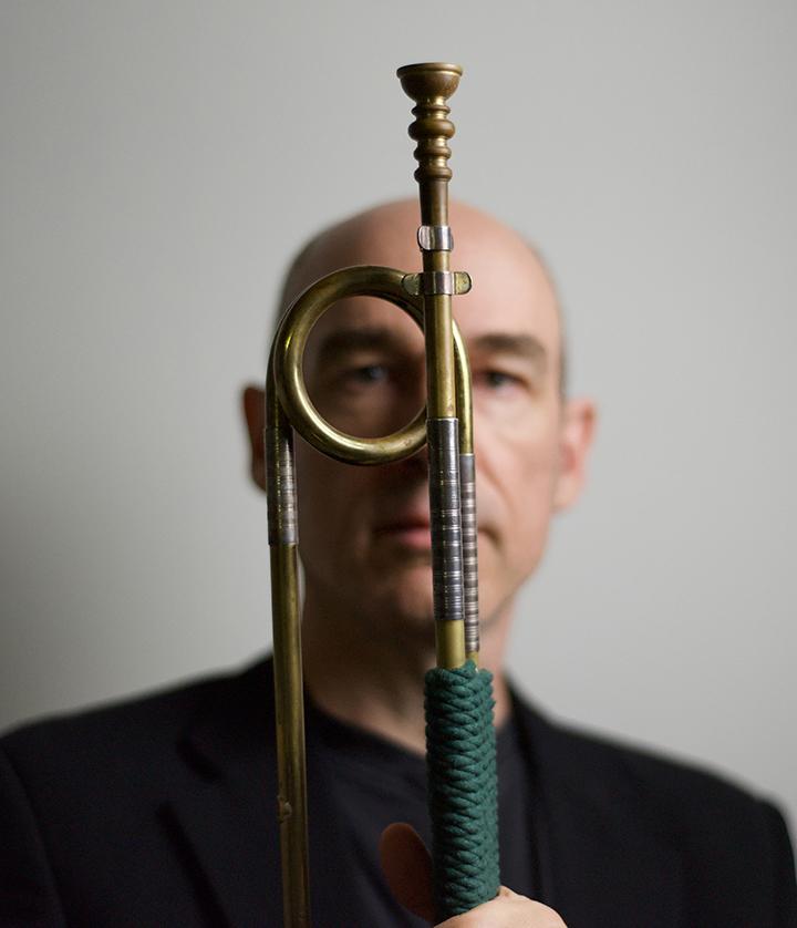 Artistic photo of Dr. Tom Pfotenhauer posed with a trumpet in the foreground