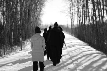 Black and white photo of a family walking on a path in the snow