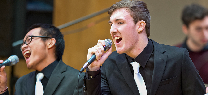 two male students singing on stage