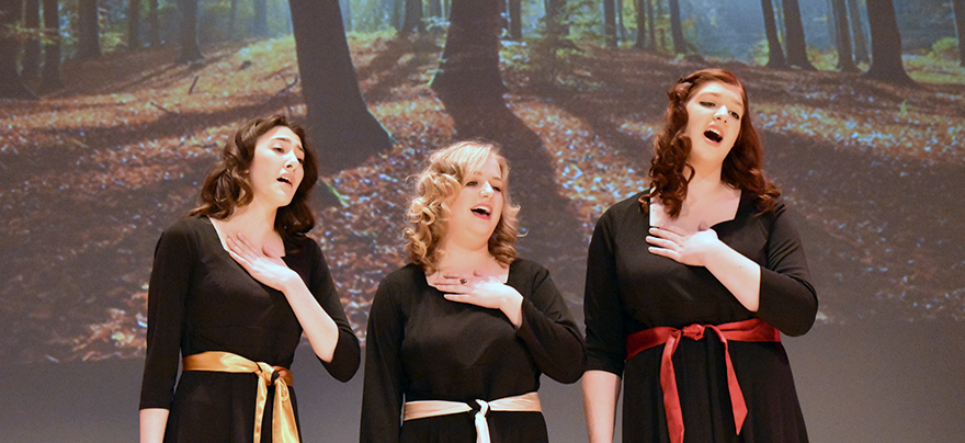 three female opera students sing on Weber stage in front of nature projections